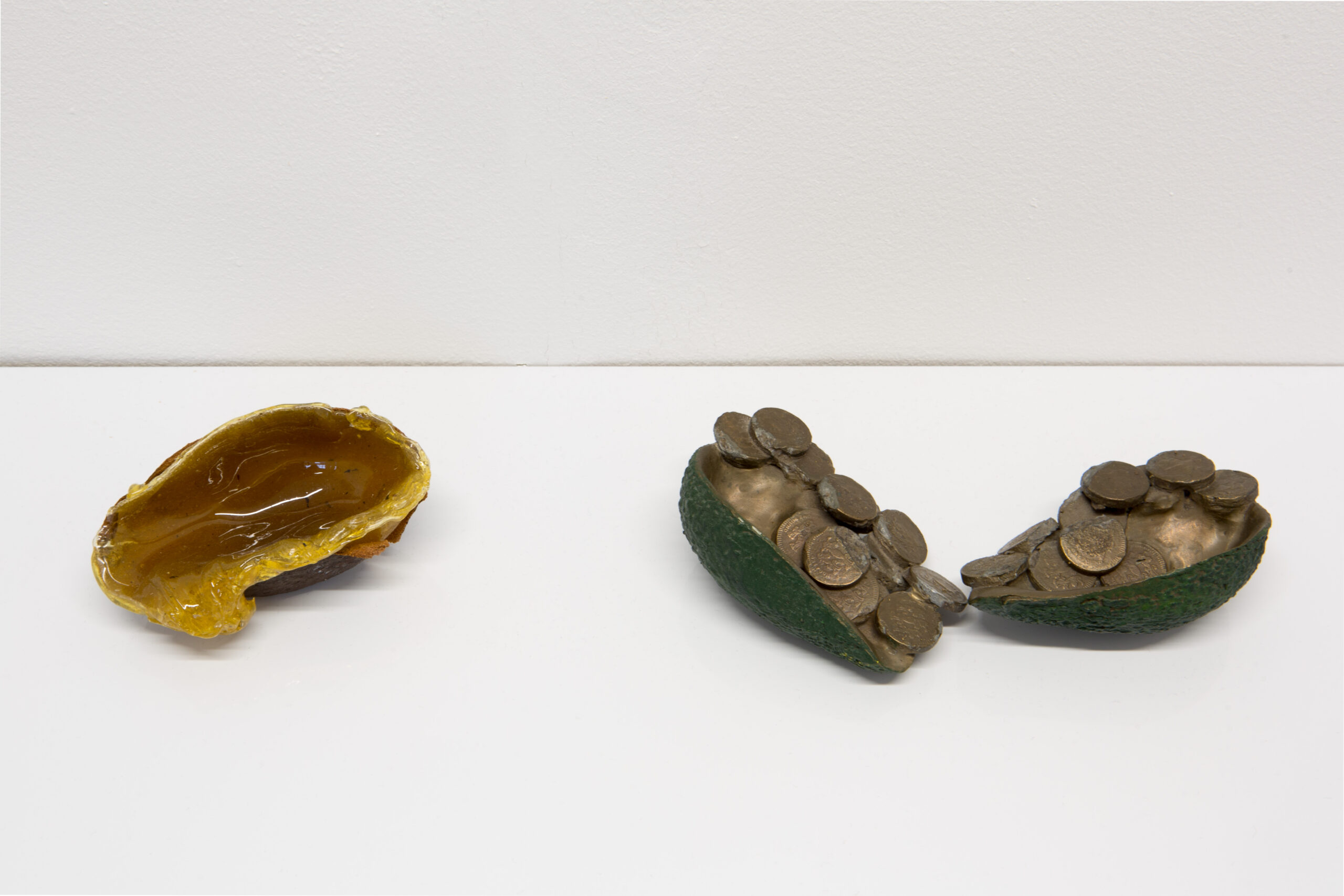 Lana Locke Avocado slime (2020) Glass wax and avocado skin, 5 cm x 11 cm x 6 cm. Lana Locke Avocado and coins (ii) (double) (2012) Bronze, 5 cm x 16 cm x 12 cm.